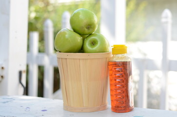 rosh hashana display fresh green apples in a wooden basket with honey outdoors with pretty white fence in the background jewish holiday  theme new year