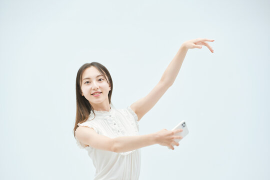 スマートフォンを持ちながら舞う若い女性
