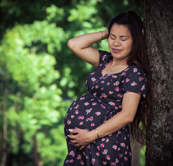 Mexican mother outside posing with her belly showing, expecting