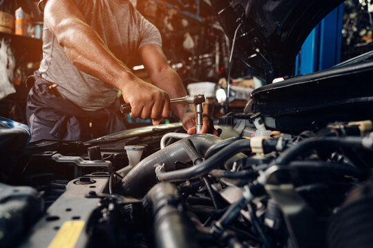 Closeup of auto mechanic are using the wrench to repair and maintenance auto engine is problems at car repair shop.