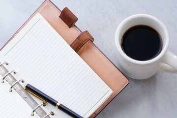 茶色の革の手帳とブラックコーヒー