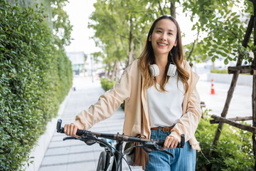Fototapeta na wymiar Lifestyle Asian young woman walking alongside with bicycle on summer in countryside outdoor, Happy female smiling walk down the street with her bike on city road, ECO environment, healthy travel