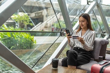 Young smart asian beautiful female lady making a payment for an online shopping purchase via her smart phone easily and successful while sitting in a cafe