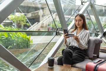 Young smart asian beautiful female lady making a payment for an online shopping purchase via her smart phone easily and successful while sitting in a cafe