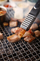 Korean table setting with grilled pork neck and side dishes on the grill 그릴 위 노릇노릇하게 항정살을 굽고 있고 반찬이 세팅되어 있는 한상차림