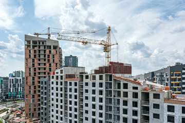 Fototapeta na wymiar cranes and residential buildings under construction against blue sky background. city construction site. aerial photo.
