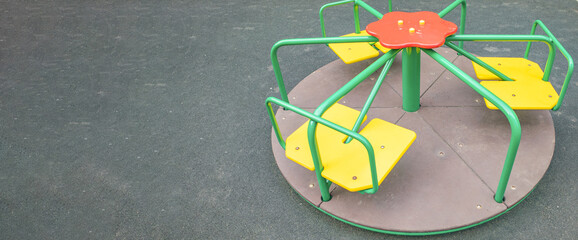 Multi-colored steel round carousel on the playground, a copy of the space on the left