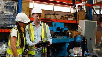 Engineers is controlling robot arm machine welding steel, worker using forcing welding with a control screen which is used for precision welding control.