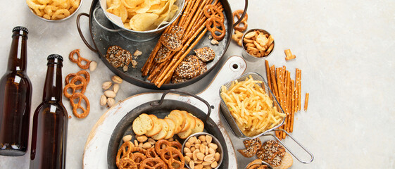 Assortment of beer and salty snacks on light background.
