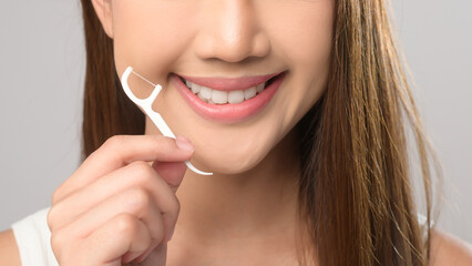 Young smiling woman holding dental floss over white background studio, dental healthcare and...