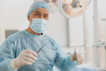 Professional doctor surgeon holding scalpel and forceps in operation room at the hospital