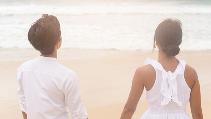 Happy young couple wearing white dress on the beach on holidays, travel, romantic, wedding concept
