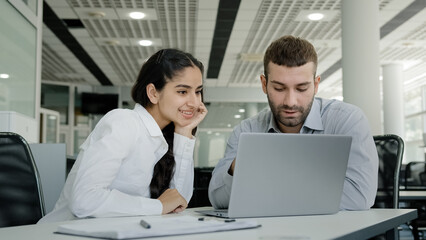 Obraz premium Woman professional manager consultant saleswoman shows man client availability goods on laptop helps to place order in online store colleagues working on teamwork work on Internet sitting in office