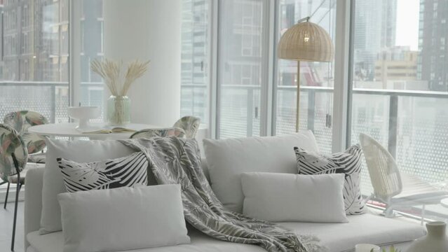 Dolly shot of decorated couch and dinning table living and dinning area of a condominium unit during a sunny afternoon.