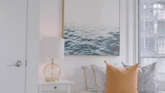 Showing a condominium badroom that with a single size bed inside and night lamp at the side and a water wave photography on the wall.