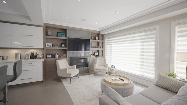 Walk into a cozy living area behind the kitchen with a sofa and coffee table and two chairs at the middle of it in a house