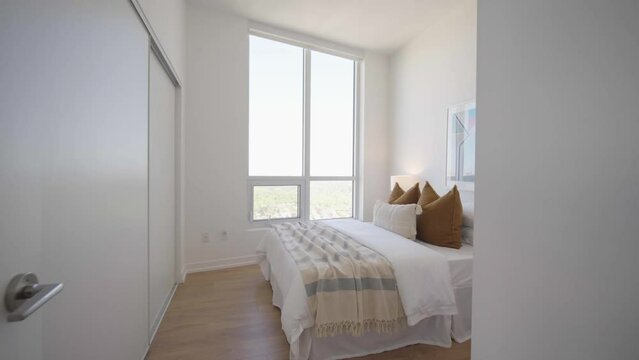 Push in and pan shot showing the bedroom of a high ceiling penthouse condominium unit during a sunny day