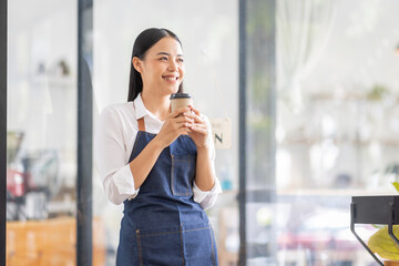 Asian woman is a waitress in an apron, the owner of the cafe stands at the door with a sign Open waiting for customers. Small business  cafes and restaurants concept,