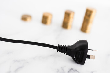 electricity costs going up, plug with growing stacks of coins in the backgroung representing prices going up