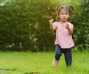 cheerful toddler girl playing grass flower in field