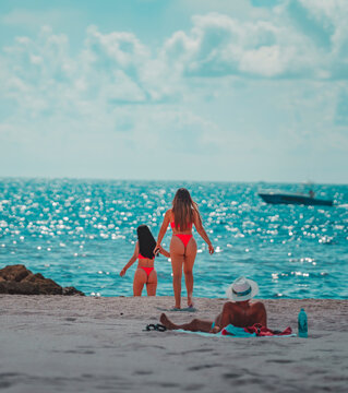 two women on the beach boat sea blue sky, man watching sugar daddy cuban Miami Beach lifestyle  