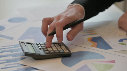 Close up of Middle Aged Businessman Writing on Paper, using Calculator