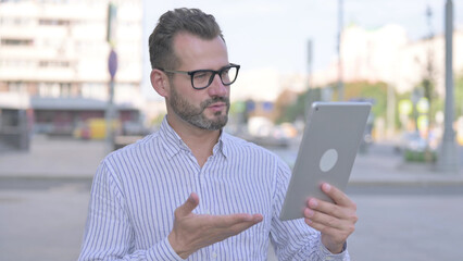 Video Call on Tablet by Young Adult Man Outdoor