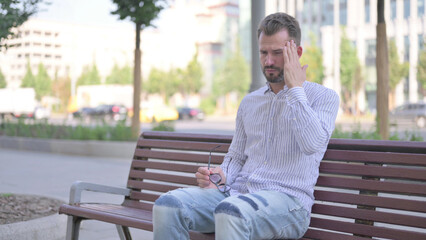 Young Adult Man with Headache Sitting Outdoor on Bench