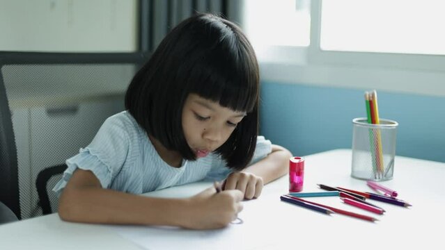 Thai Asian kid girl, age 5 to 7 years old, cute face, reading and drawing. happily in the classroom at home She is a child who loves studying and likes to practice knowledge making her a smart child.