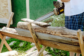 chainsaw in the hands of a worker cutting firewood, close-up