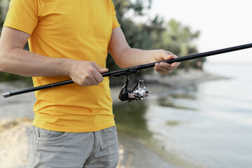 Close-shot of man hands holding a fishing-rod on the foreground. Hobby and activity