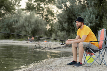 Adult man fishing from shore near cottage on lake in Finland at summer. leisure and people