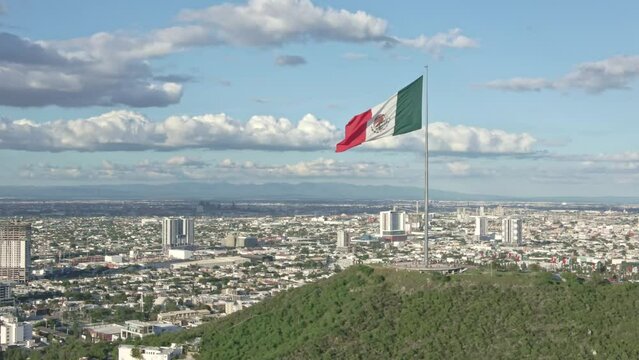 Mexico flag waving on Cerro del Obispado, Monterrey aerial view dolly zoom