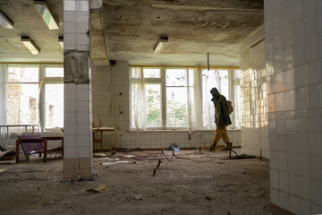 Man walking in an abandoned building. wandering men. man in a cloak with a hood. Post apocalypse....