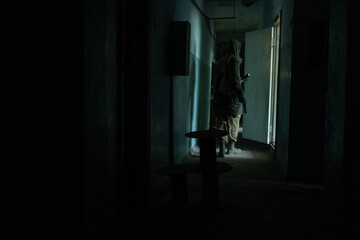 a man walking in a dark corridor of abandoned build, with flashlight in dark