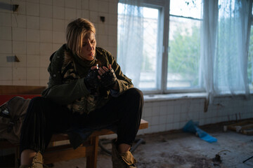 Special female soldier after the fight sitting in ruined building smoking cigarette staring at the...