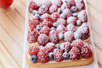 French blueberry and raspberry tartlets sprinkled with powder close up. Top view food. Aesthetic food