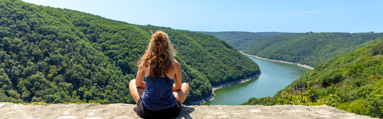 Rear view of woman sitting and looking at river dordogne and mountain