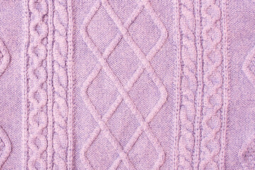 Purple warm knitted sweater with a pattern. Purple woolen sweater, knitted sweater texture, knitted background. Purple knitted textured background with a pattern closeup