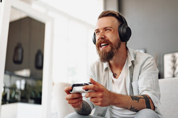 Young bearded man playing video games while sitting on the couch at home © fotofabrika