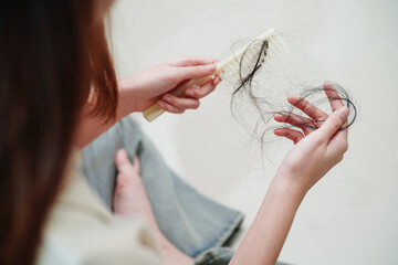 Asian woman have problem with long hair loss attach to comb brush..