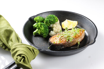 Fried salmon steaks with lemon butter sauce garnish with micro greens.