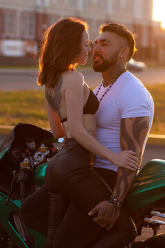 Couple hugging near motorbike at sunset