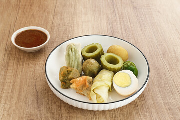 Siomay Bandung (Shumay) or steamed dumplings with boiled egg, tofu, potatoes and cabbage roll. Indonesian traditional street food with peanut sauce and soy sauce, served with green lime.
