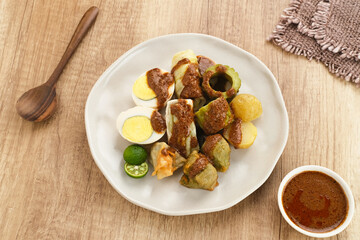 Siomay Bandung (Shumay) or steamed dumplings with boiled egg, tofu, potatoes and cabbage roll. Indonesian traditional street food with peanut sauce and soy sauce, served with green lime.
