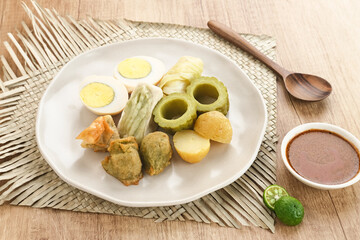 Siomay Bandung (Shumay) or steamed dumplings with boiled egg, tofu, potatoes and cabbage roll. Indonesian traditional street food with peanut sauce and soy sauce, served with green lime.
