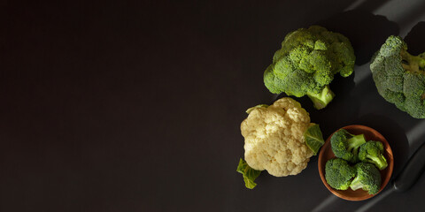 Broccoli and cauliflower on dark background, top view.
