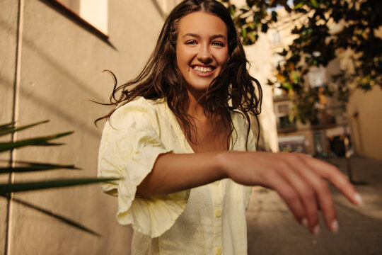 Cheerful young caucasian brunette girl resting outdoors on weekends in warm weather. Lady smiles, wears summer sundress. Lifestyle concept