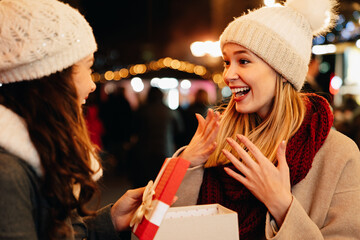 Portrait of happy women friends exchanging christmas present. Holiday people happiness concept