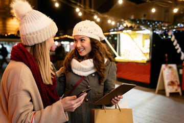 Portrait of happy women enjoying christmas shopping together in the city
